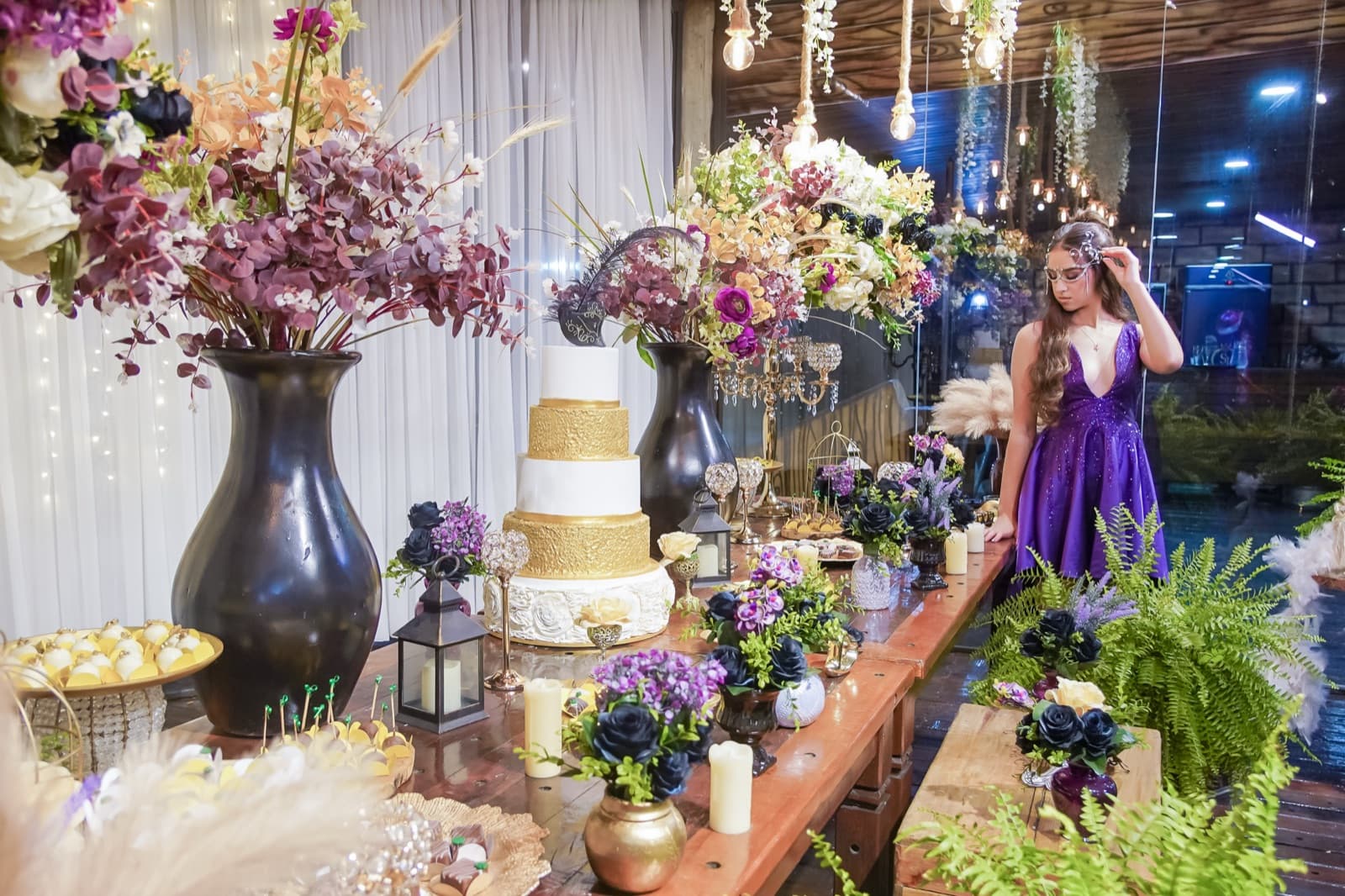 Debutante admirando a mesa de doces decorada com flores e velas