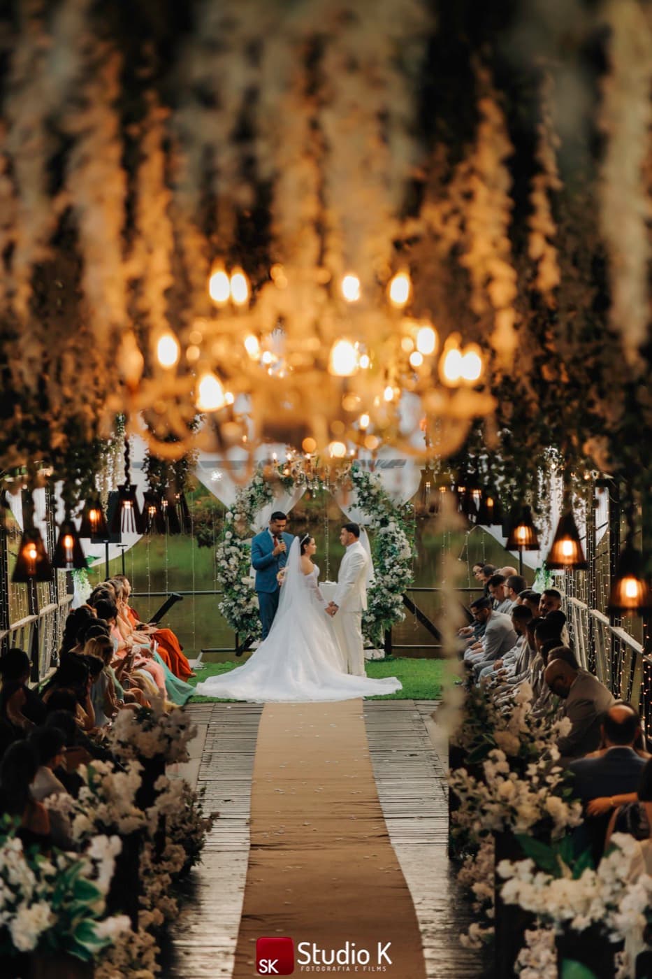Casal no altar durante a cerimônia, visto pelo corredor florido