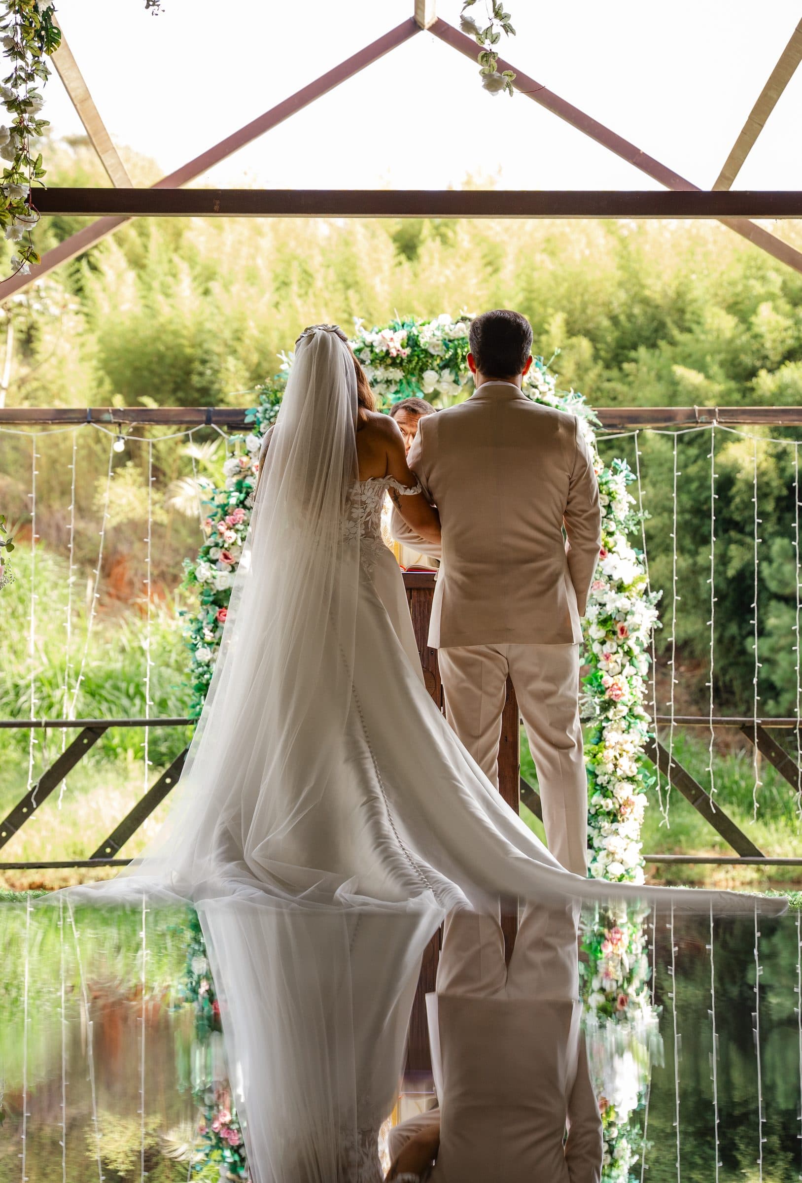 Casal no altar do Fazenda Santa Isabel Premium, com reflexo no espelho d'água